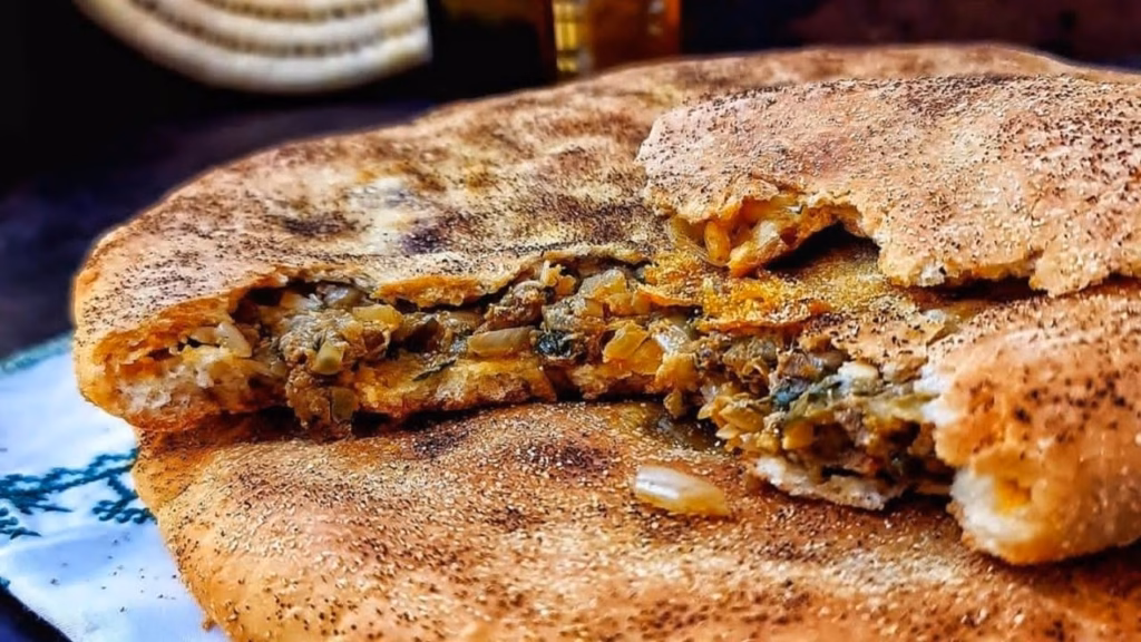 Medfouna torn open to show the spiced meat and onion filling inside